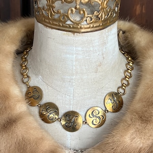 May include: A gold chain necklace with round, engraved medallions featuring the letters "S", "F", "H", "Y", and "S".