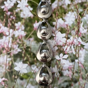 May include: A silver bracelet with a series of linked oval-shaped charms. Each charm has a smooth, round ball in the center.