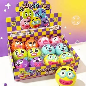 Può includere: Una scatola espositiva in cartone contenente diversi giocattoli morbidi, rotondi e colorati con varie espressioni facciali. La scatola presenta un motivo a scacchi giallo e viola, la scritta SQUISHY TOY e SUPER FUN. Un giocattolo giallo con occhiali blu è posto davanti.