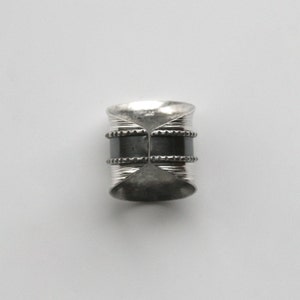 May include: A silver ring with two black bands and a textured design.