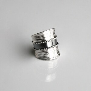 May include: A silver ring with a textured band and a black band with a beaded edge.