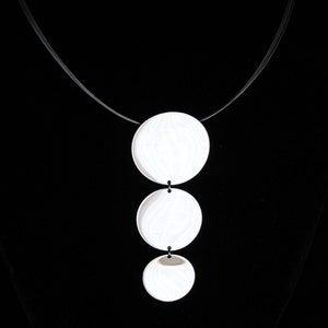May include: A silver necklace with three round pendant charms. The charms are layered and hang from a black cord.