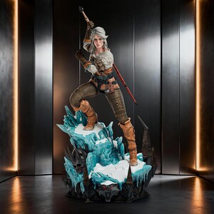 May include: A detailed collectible statue of a silver-haired warrior figure in a dynamic combat pose, wearing a white shirt, brown trousers, and leather boots, standing on a base of jagged blue ice with a dark wolf emblem at the front.