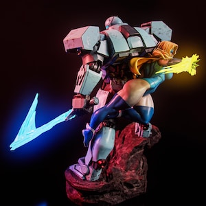 Op de afbeelding: Een verzamelfiguur met een grote, lichtblauwe gepantserde robot die een zwaard met een gloeiend blauw energieblad vasthoudt, terwijl een blond personage in een blauw pak en gele cape een felle gele energiestraal uit één hand schiet.