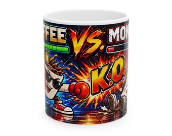 May include: A white ceramic mug featuring a colorful pixel art graphic of a coffee cup wearing sunglasses and red boxing gloves, punching a character labeled MON. The text reads COFFEE VS. MON and K.O. with health bars and explosions.