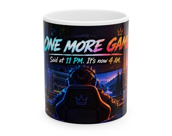 May include: A white ceramic mug featuring a colorful graphic of a gamer sitting in a chair before a computer screen. The text reads: ONE MORE GAME. Said at 11 PM. It's now 4 AM. The design includes a small crown icon and vibrant neon hues.