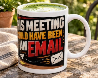 May include: A white ceramic mug filled with green matcha tea, featuring the black, yellow, and red text "THIS MEETING COULD HAVE BEEN AN EMAIL" alongside a graphic illustration of a paper airplane and a white envelope on a dark background.