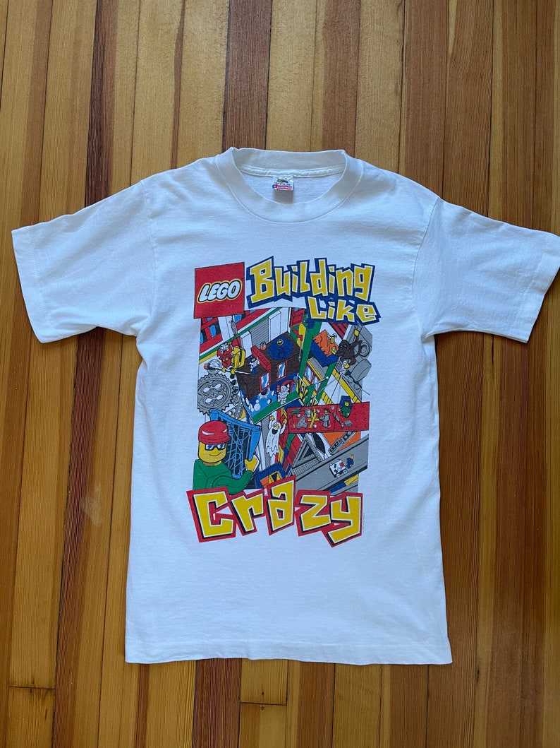May include: White t-shirt with a colorful LEGO graphic that says "Building Like Crazy".