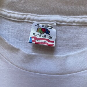 May include: White Fruit of the Loom tag with a red, white, and blue American flag. The tag says "Adult S 100% Cotton Preshrunk Fruit of the Loom Made in U.S.A."