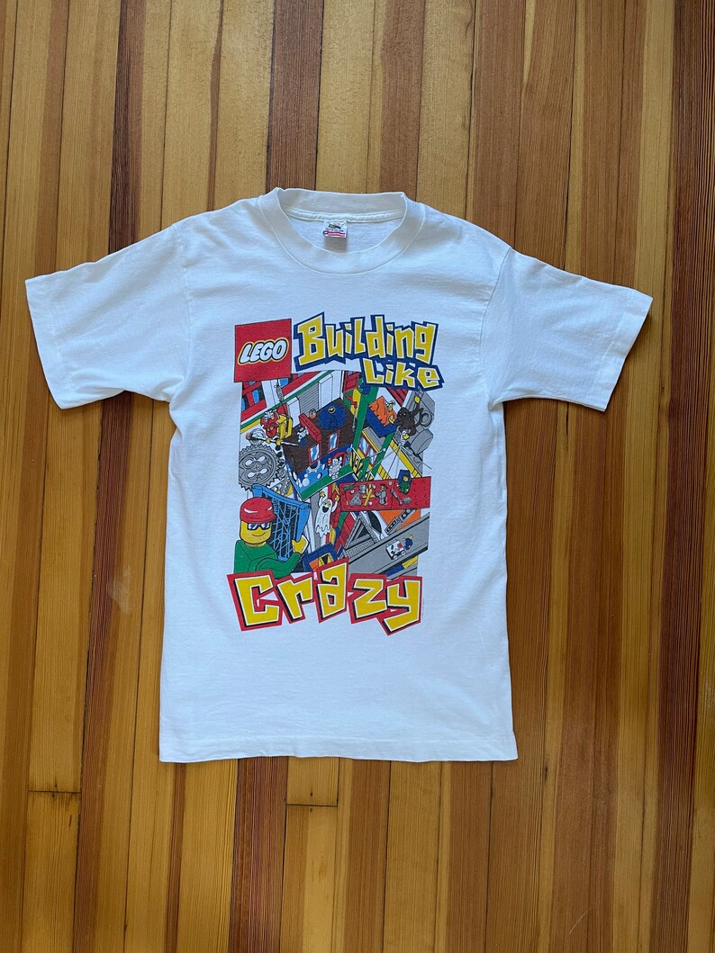 May include: White t-shirt with a colorful LEGO graphic that says "Building Like Crazy".