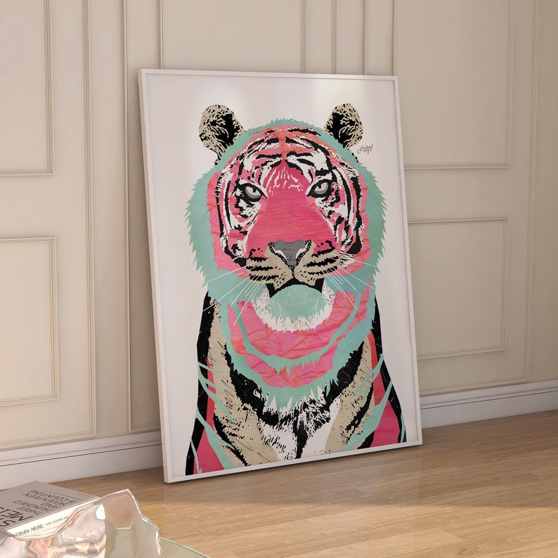 Puede incluir: Una impresi&oacute;n art&iacute;stica enmarcada con una ilustraci&oacute;n de un tigre colorido. La cara del tigre es predominantemente rosa, con acentos de color turquesa, negro y beige. La obra de arte est&aacute; sobre un fondo blanco y enmarcada en un borde blanco. La obra de arte est&aacute; apoyada contra una pared.