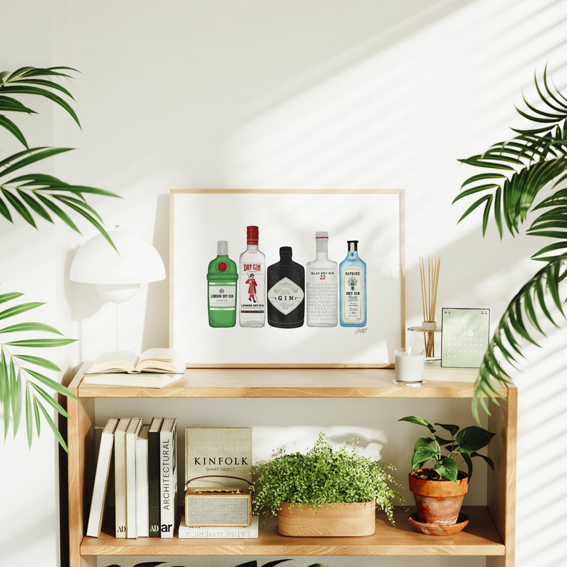 May include: A framed print featuring illustrations of five different gin bottles. The bottles are in various colors, including green, red, black, and blue, and are labeled with the names of the gin brands. The print is displayed on a wooden shelf with books and plants.