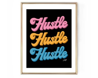 May include: A framed art print with the word "Hustle" in pink, gold, and blue, stacked vertically on a black background. The print has a gold frame and a white border.