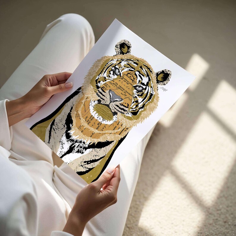 Puede incluir: Una impresi&oacute;n art&iacute;stica detallada de la cara de un tigre, con un collage de texto y varios tonos de marr&oacute;n, negro y blanco. Los ojos del tigre son azules. La obra de arte es sostenida por una persona vestida de blanco.