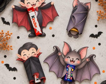 Könnte beinhalten: Vier Halloween-Papierhalter für Schokoriegel. Zwei zeigen Comic-Vampire mit rot gefütterten Umhängen, einer ist eine eingewickelte Fledermaus und einer hält einen blauen Smarties-Riegel. Ein Vampir hält einen Kinder-Schokoriegel.