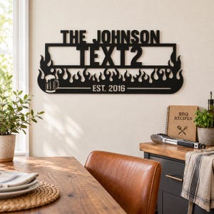 May include: A black metal wall sign featuring the text THE JOHNSON and TEXT2, with a flame design along the bottom edge, a beer mug icon on the left, and the text EST. 2016 centred below the flame pattern in a horizontal layout.