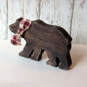 May include: A wooden bear cutout painted black with a red and white plaid ribbon tied around its neck.
