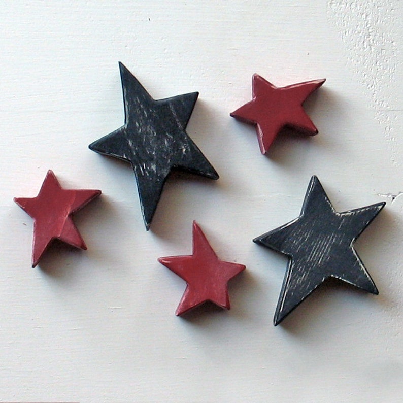 May include: Five wooden stars, two are red and three are black. The stars are painted and have a distressed look.