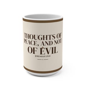 May include: A cylindrical ceramic mug with a cream-colored body and dark brown trim at the top and bottom. The text reads THOUGHTS OF PEACE, AND NOT OF EVIL, followed by JEREMIAH 29:11 and a small decorative horizontal line with a star.