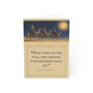 May include: A greeting card featuring an illustration of three figures riding camels across a desert landscape under a starry night sky with a bright sun. The text reads, "When they saw the star, they rejoiced with exceeding great joy." - Matthew 2:10 -