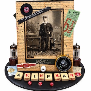 May include: A mixed-media assemblage featuring a vintage portrait of a man labeled Chadwick Buford, Gentleman. The piece includes a compass, two vacuum tubes, a green ticket, and Scrabble tiles spelling A FINE MAN, plus three red dice.