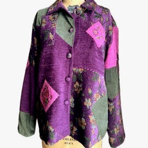May include: A long-sleeved button-down jacket featuring a patchwork design in shades of purple, olive green, and bright pink. The garment includes floral patterns, solid-colored panels, and a collar, with a visible brand label at the neckline.