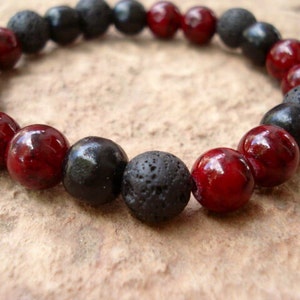 May include: A bracelet made of black and red beads. The bracelet is made of lava rock and wood beads.