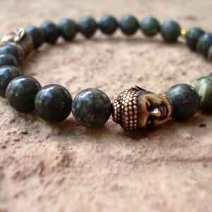 May include: A green stone beaded bracelet with a gold-toned Buddha head charm.