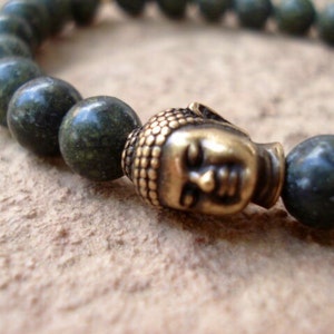 May include: A green stone beaded bracelet with a gold Buddha head charm.