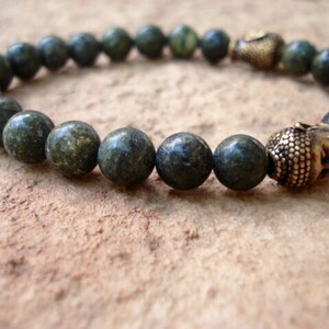 May include: A green stone beaded bracelet with two gold Buddha head charms.
