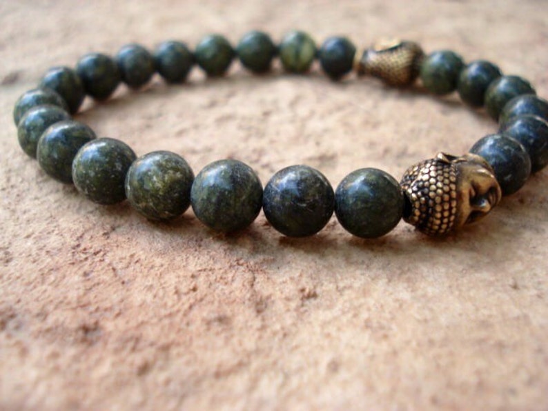 May include: A green stone beaded bracelet with two gold Buddha head charms.