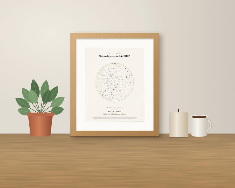 May include: A framed star map print in a light wood frame featuring a circular constellation chart, the text Saturday, June 14, 2025, and Austin, Texas. The print is displayed alongside a potted green plant, a candle, and a white mug.