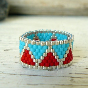 Puede incluir: Un anillo de cuentas con un patrón geométrico en rojo, turquesa y plata.