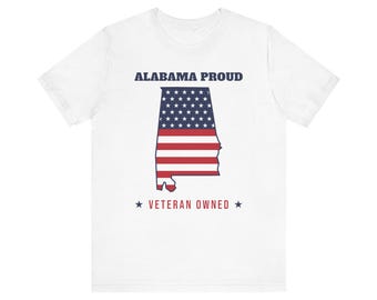 Op de afbeelding: Een wit t-shirt met korte mouwen met de tekst ALABAMA PROUD in donkerblauw boven een afbeelding van de staat Alabama gevuld met het Amerikaanse vlagpatroon, met de tekst VETERAN OWNED in rood geflankeerd door twee donkerblauwe sterren.