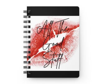 Puede incluir: Un cuaderno de espiral con cubierta negra y un panel central rectangular blanco. El panel muestra un gran gráfico de marca de beso de lápiz labial rojo con el texto cursivo negro All The Good Stuff impreso en el centro.