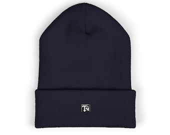 May include: A dark navy blue knit beanie with a folded cuff. Centered on the front of the cuff is a small square patch featuring the white letters TN with a small mountain graphic integrated into the design, set against a dark background.