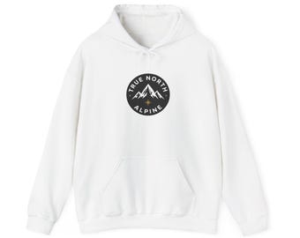 May include: A white hooded sweatshirt featuring a black circular graphic on the chest. The graphic displays a white mountain range illustration, a small gold star, and the text True North Alpine in a circular white sans-serif font.