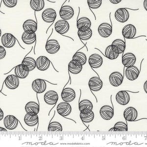 May include: White fabric with a black and white repeating pattern of yarn balls. The fabric has a ruler with the word "moda" printed on it.