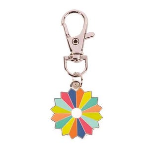 May include: A silver keychain with a colorful flower charm. The flower has a white center and is made up of 12 petals in shades of blue, green, yellow, orange, and pink.