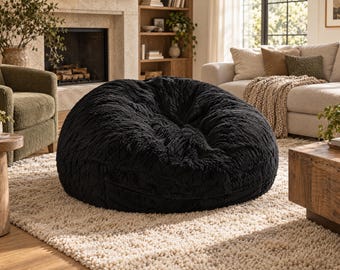 May include: A large, round, black bean bag chair covered in a thick, shaggy, faux-fur material. The surface of the chair features a dense, textured pile that creates a soft, plush appearance with deep folds and a rounded, voluminous shape.