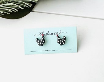 May include: A pair of black and white polka dot chicken earrings with red combs. The earrings are on a blue card with the text "the glass bird" and "handmade jewelry".