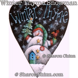 May include: A heart-shaped wooden sign with a winter theme. The sign features a snowman holding a small pine tree, a red bird, and the words "Winter Thyme" in blue lettering. The background is black with white snowflakes.