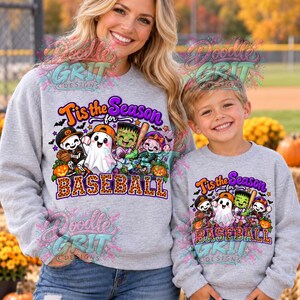 Puede incluir: Dos sudaderas gris claro de cuello redondo con un estampado gráfico de personajes de dibujos animados, incluyendo un esqueleto, un fantasma, el monstruo de Frankenstein y un zombi jugando al béisbol con el texto 'Tis the Season for BASEBALL'.