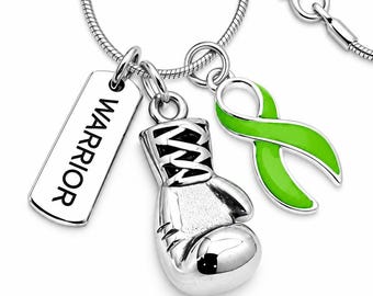 May include: A silver-toned necklace featuring three charms: a rectangular tag engraved with the word WARRIOR, a detailed boxing glove, and a bright lime green awareness ribbon. The charms hang from a smooth, flexible silver-toned snake chain.