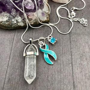 Puede incluir: Un collar de cadena de plata con un colgante de cristal de cuarzo transparente, un dije de cinta turquesa y un pequeño dije de piedra turquesa.