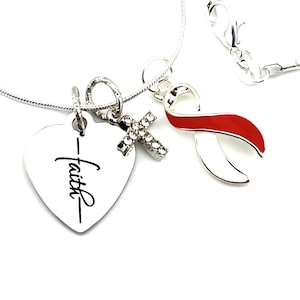 Può includere: Collana d'argento con un ciondolo a forma di cuore che dice "Fede", un ciondolo a forma di croce con pietre preziose e un ciondolo a forma di nastro rosso e bianco.