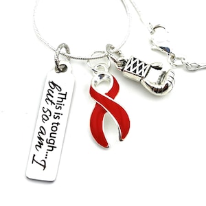 Può includere: Collana d'argento con un ciondolo a nastro rosso, un ciondolo a guanto da boxe argentato e un'etichetta d'argento con il testo "This is tough... but so am I".