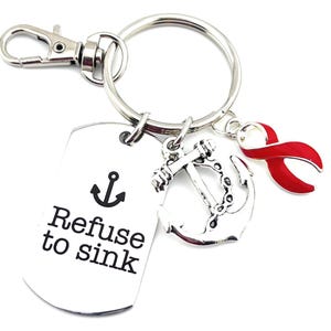 May include: Silver keyring with a red ribbon charm, an anchor charm, and a silver tag that says "Refuse to sink" with a small anchor symbol.