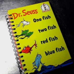 May include: A yellow spiral bound notebook with the title "Dr. Seuss" and the words "One fish, two fish, red fish, blue fish" printed on the cover.
