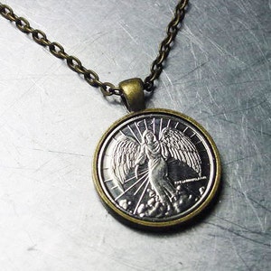May include: A silver pendant necklace with a bronze chain. The pendant features a detailed image of an angel with wings spread wide.
